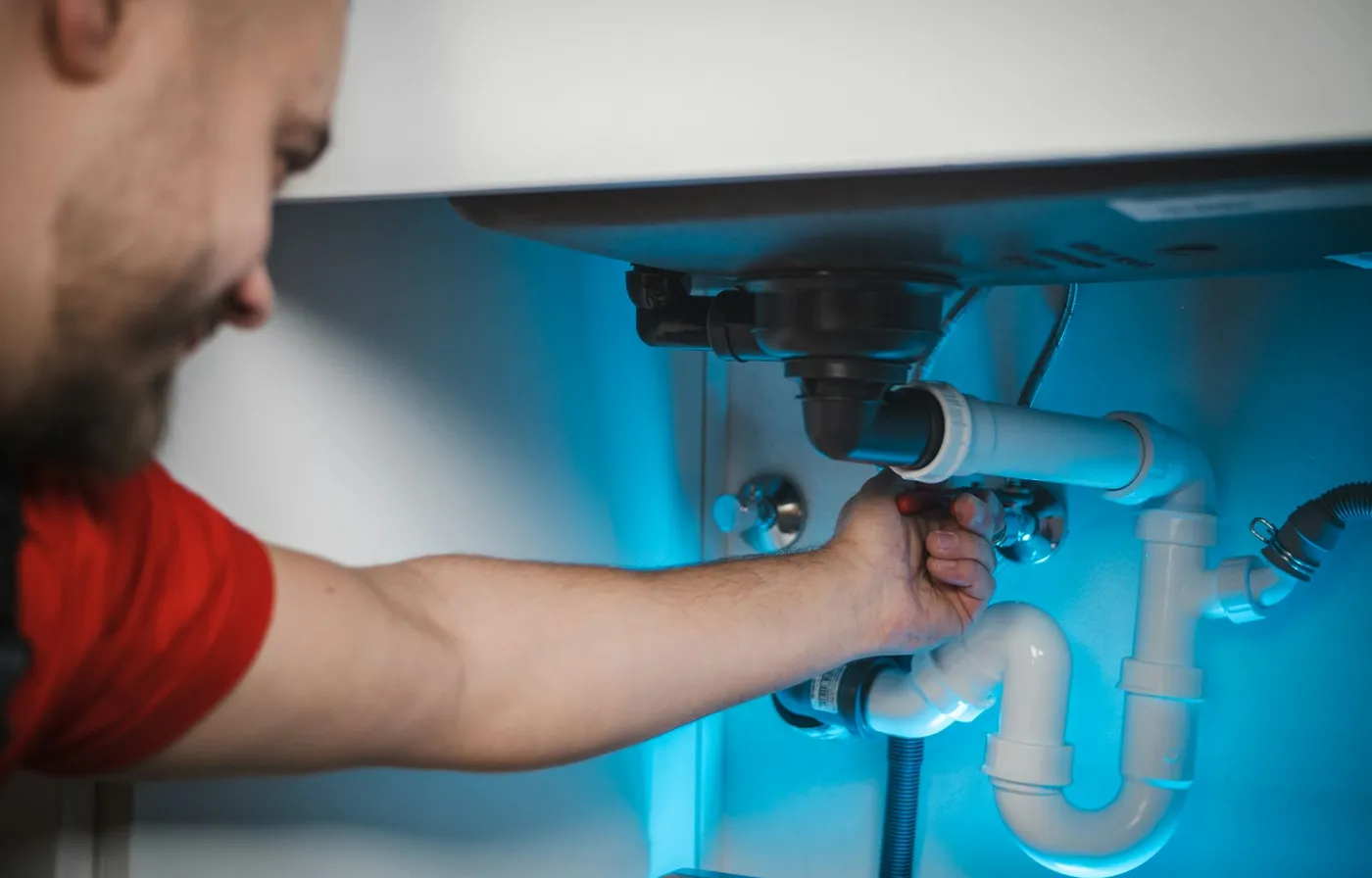 Plumber repairing pipes under a sink during a home service call